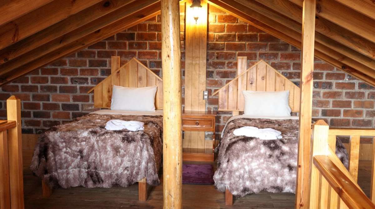 Cozy wooden loft sleeping area at Hotel y Cabañas Alan